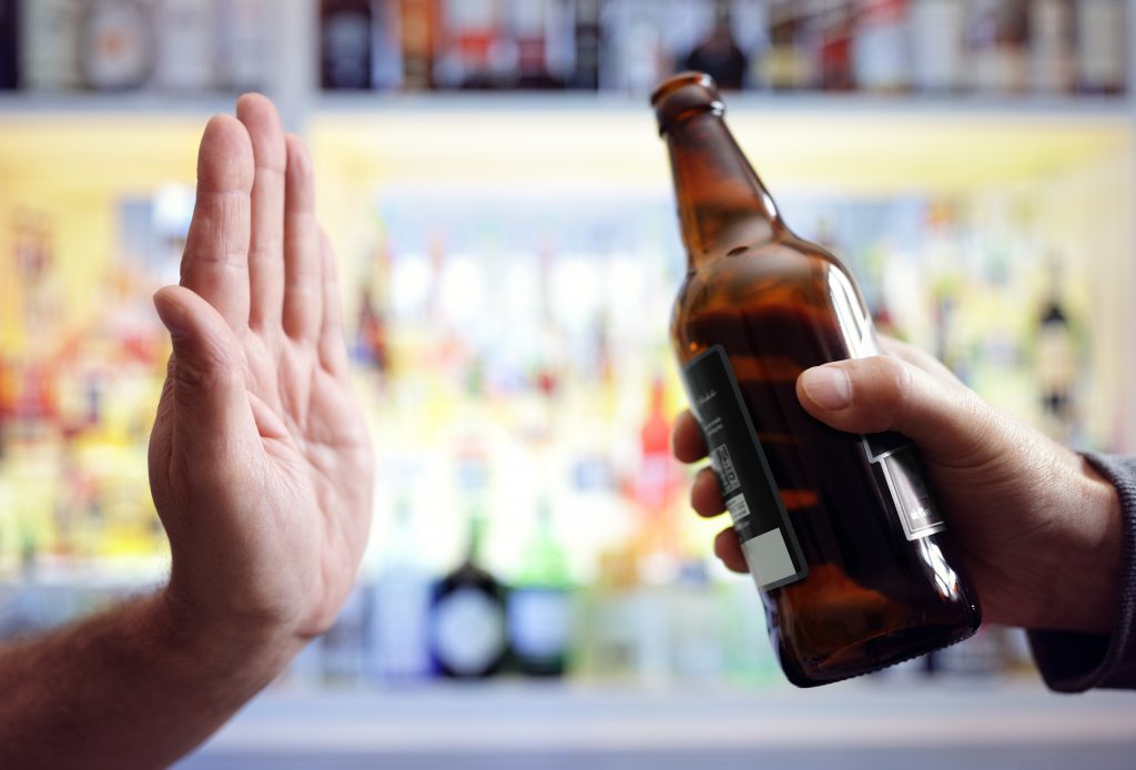 hand rejecting a bottle of beer and quitting alcohol