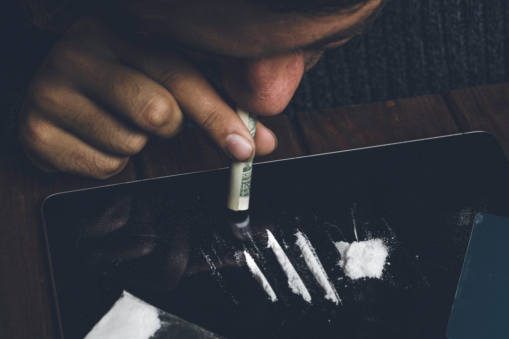 man snorting cocaine with a rolled up bank note
