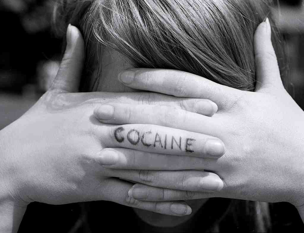 women with her hands over her eyes and cocaine written on finger