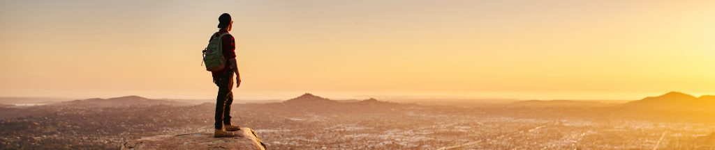 man hiking on top of hill in california over looking san diego at sunset