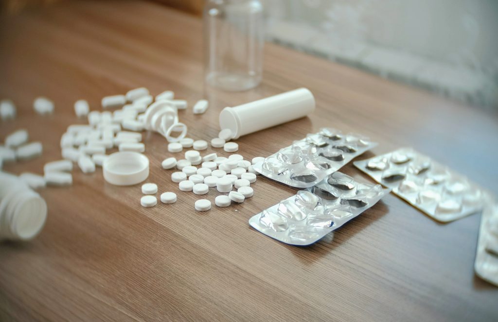 Round white tablets and oval pills on the table with empty boxes and blisters.