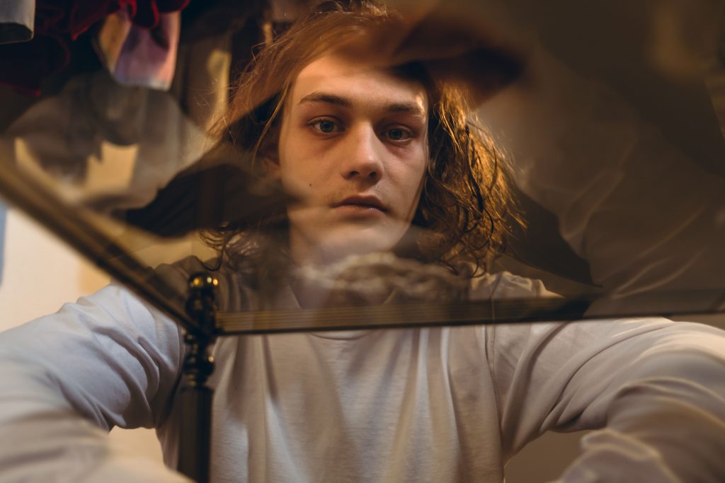boy looking through a glass table at some drugs