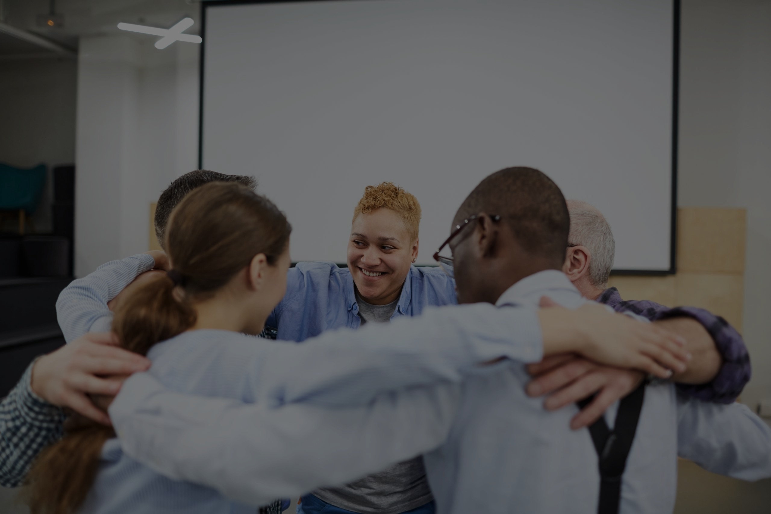 a group of men and women together in a huddle at an alcohol counselling meeting