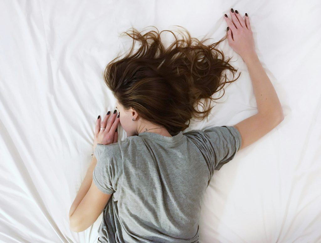woman sleeping face down with brown hair and a grey t shirt on