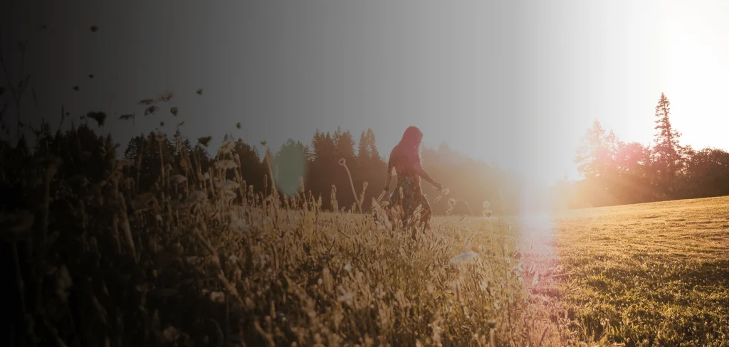 Girl walking through fields at sundown